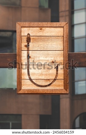 A large fishing hook is depicted on a wooden plank Royalty-Free Stock Photo #2456034159
