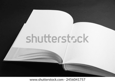 One open photo album on black background, closeup. Space for text