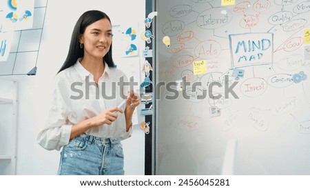 Professional attractive female leader presents creative marketing plan by using brainstorming mind mapping statistic graph and colorful sticky note at modern business meeting room. Immaculate. Royalty-Free Stock Photo #2456045281