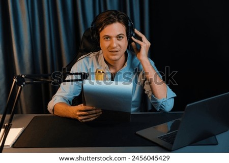 Host channel in smart broadcaster with talking show on live social media streaming with script note reading to listener with record video streamer in warm light night time at modern studio. Pecuniary.