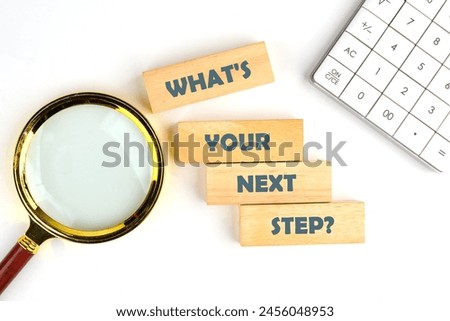 What is your next step symbol on wooden blocks on a white background near a calculator and a magnifying glass