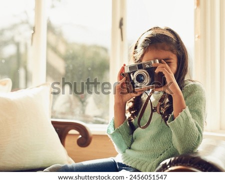 Home, girl and child with vintage camera, photography and memory with fun, playful and relax in living room. Apartment, retro or kid taking picture, creative and hobby with lens, learning or creative