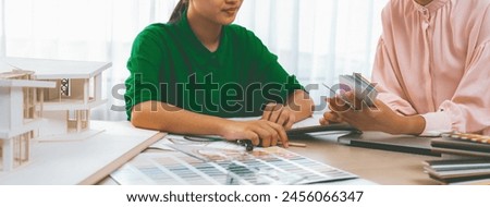 Smart interior design team choose color for project carefully by using color swatches with house model and color swatches scatter around on meeting table. Creative design concept. Variegated.