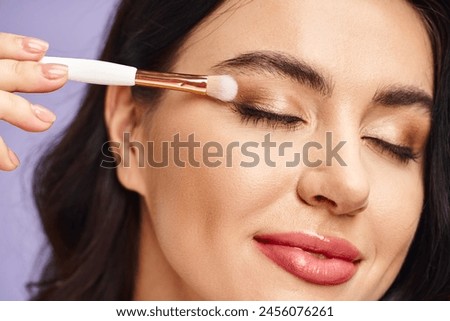 Beautiful woman enhancing natural beauty with a brush in her eye.