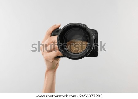 Photographer with camera on light grey background, closeup