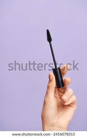 A woman enhances her natural beauty with black mascara in hand.