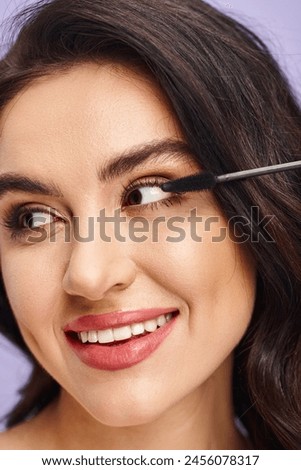 A woman delicately applying mascara with a brush to enhance her eye.