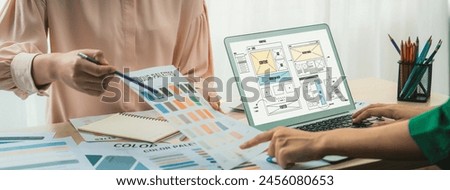 Cropped image of interior designer presents color from color swatches while laptop displayed website wireframe designs for mobiles app and website. Creative design and business concept. Variegated.