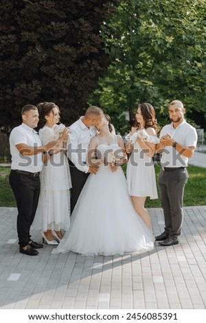 A group of people are posing for a picture, including a bride and groom. The bride is wearing a white dress and the groom is wearing a suit. The group is standing on a brick walkway