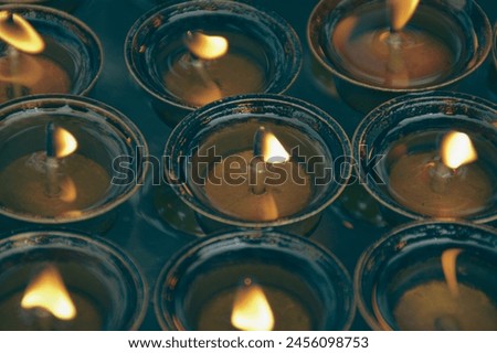 Overhead view of lit tibetan brass ghee lamps or butter lamps, symbolizing spirituality and used in sacred Buddhist rituals in Swayambunath Temple in Kathmandu, Nepal