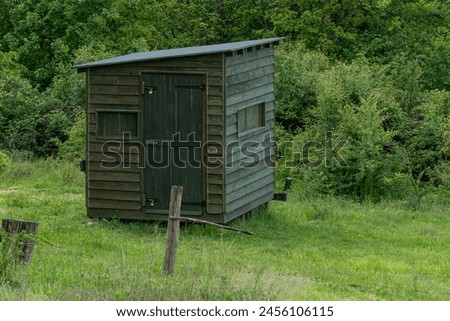 A wooden wildlife photography hide in woodland.