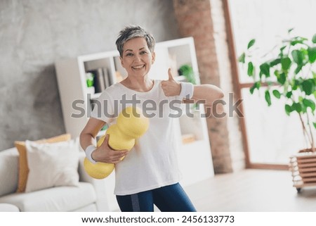 Photo of nice pensioner woman thumb up hold massage roll sportswear home exercising routine living room healthy lifestyle