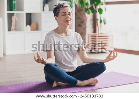 Full length photo of nice pensioner woman show mat meditate exercises sportswear home exercising routine living room healthy lifestyle