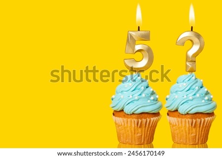 Birthday cake with lit Number 5 and Question Mark candle - Photo on Yellow background.