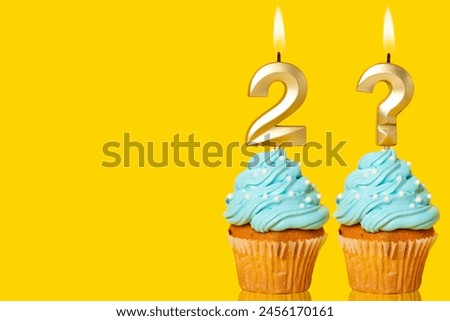 Birthday cake with lit Number 2 and Question Mark candle - Photo on Yellow background.
