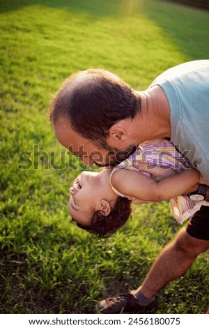 young father holding happy baby daughter in the air at sunset at the park outdoors in nature .concept of harmony in fatherhood, sharing happy moments together.