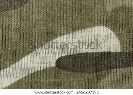 A close up of a piece of camouflage fabric. The fabric is a mix of brown and white, with a pattern that resembles a camouflage design. Scene is one of focus and attention to detail