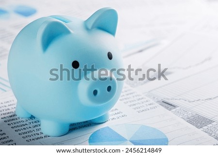 Moneybox for money on the background of documents and financial charts. Investment and capital accumulation concept