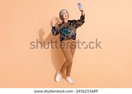 Fill size photo of good mood retired woman dressed print shirt waving hand say hi on smartphone isolated on pastel color background