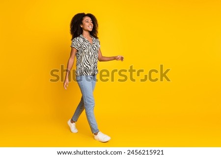 Portrait photo of steps young charming woman curly hair in trendy zebra print shirt and jeans isolated on yellow color background