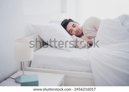 Photo of young attractive man peaceful sleeping lying in comfy bedroom white interior inside