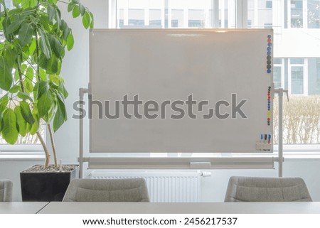 Whiteboard on window background. Close-up. green plant