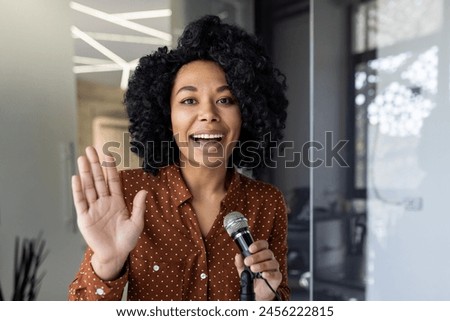 A cheerful African American businesswoman hosts a podcast, speaking into a microphone with a bright smile, conveying excitement and professionalism.