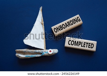 Onboarding Completed symbol. Concept word Onboarding Completed on wooden blocks. Beautiful deep blue background with boat. Business and Onboarding Completed concept. Copy space