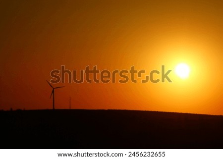 A sunset behind a wind turbine
