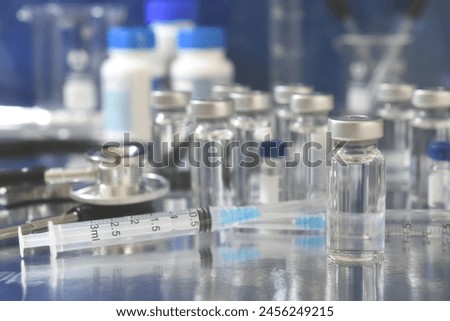 Vaccine booster concept faded background - vials of generic vaccines with syringe and stethoscope Royalty-Free Stock Photo #2456249215