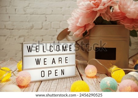 Welcome We are Open text on lightbox on wooden background