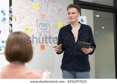Professional male leader presents start up project by using mind map, colorful sticky notes and business statistic graph with confident while investor listening at business meeting. Immaculate. Royalty-Free Stock Photo #2456297615