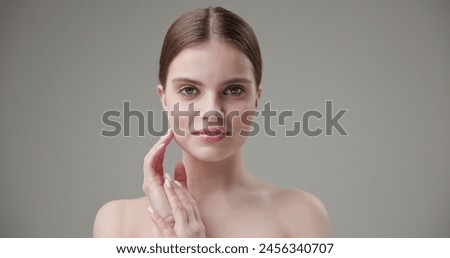 Beauty, health, cosmetics, anti-aging therapy and skin care concept - young beautiful brunette Caucasian woman touching face and looking at camera