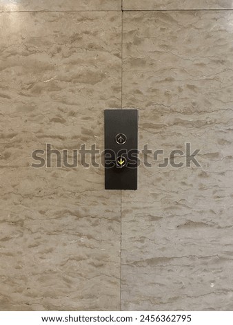 Elevator button with the down button activated on the marble background