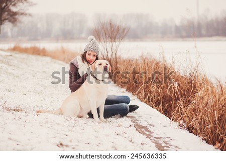 Girl stroking dog in winter park