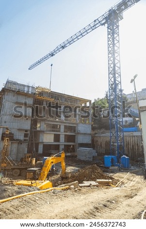 Tower crane at the construction site in the sunlight. Special equipment at the construction site. Vertical photo.