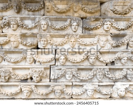 A detailed frieze in Aphrodisias, Turkey, beautifully displaying a series of sculpted Greco-Roman faces with ornamental garlands. Royalty-Free Stock Photo #2456405715