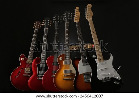 Group photo of electric guitars taken against a dark background