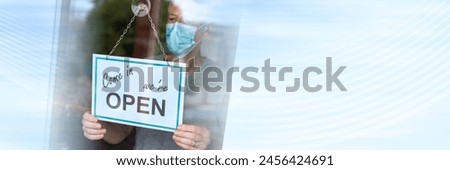 Store owner hanging come in we're open sign on window; panoramic banner