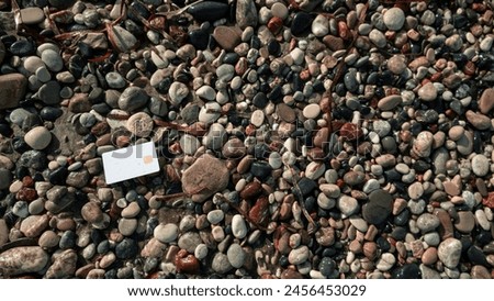 mound of rocks, each boasting unique blend of colors and sizes, epitomizing the allure of natural beauty and ruggedness, with a white bank card, juxtaposing human convenience against nature's rawness. Royalty-Free Stock Photo #2456453029