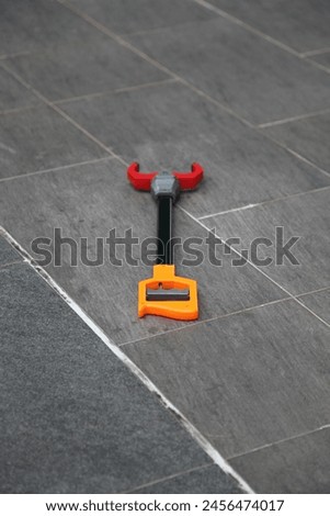 Exterior photo visual view of a claw toy plier toy clamp toy on a grey gray ground floor make from textured tiles left alone