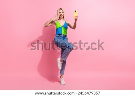 Full size photo of satisfied woman wear colorful top jeans show thumb up doing selfie on smartphone isolated on pink color background