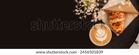 french or italian breakfast croissant and cappuccino on circle coffee shop table with zamioculcas home interior plant. homemade bakery, filled baked goods. top view, flat lay. trendy food photo