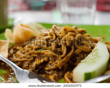 Fried noodles with a rectangular texture sprinkled with henna on a green plate