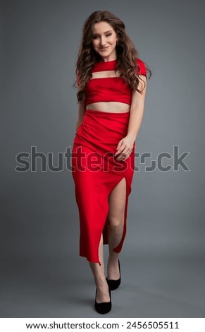 Studio portrait of young beautiful woman in red dress against gray background