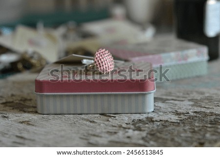 Picture of a ring on top of a retro design trinket box with lines and pattern placed on top of a rustic surface.