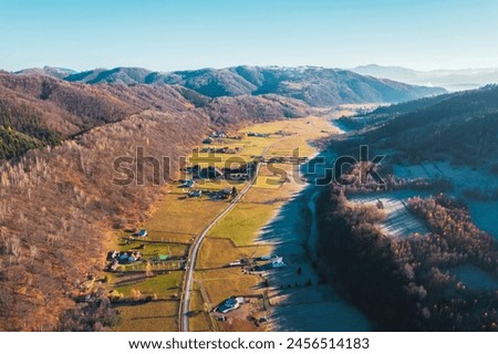 Rolling hills, vibrant green forests, and winding rivers compose a breathtaking landscape in the mountainous rural area captured from above Royalty-Free Stock Photo #2456514183
