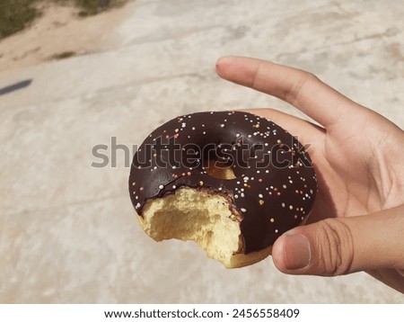 Chocolate donut in photographer's hand