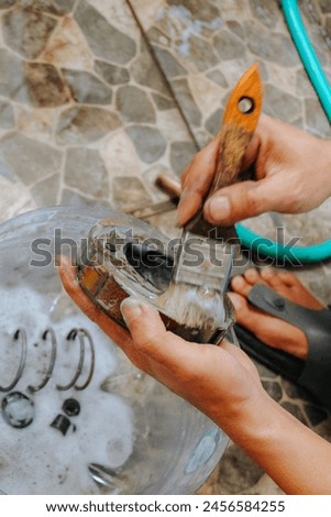 close up of someone's hands washing motorbike spare parts