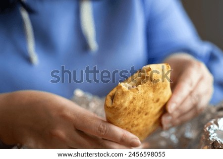 Woman's hands holding a rectangular pie with a bite taken out